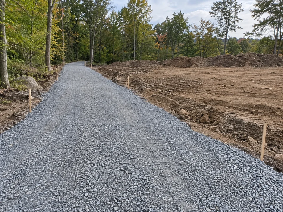 Prepared gravel access lane beside unfinished site earthworks