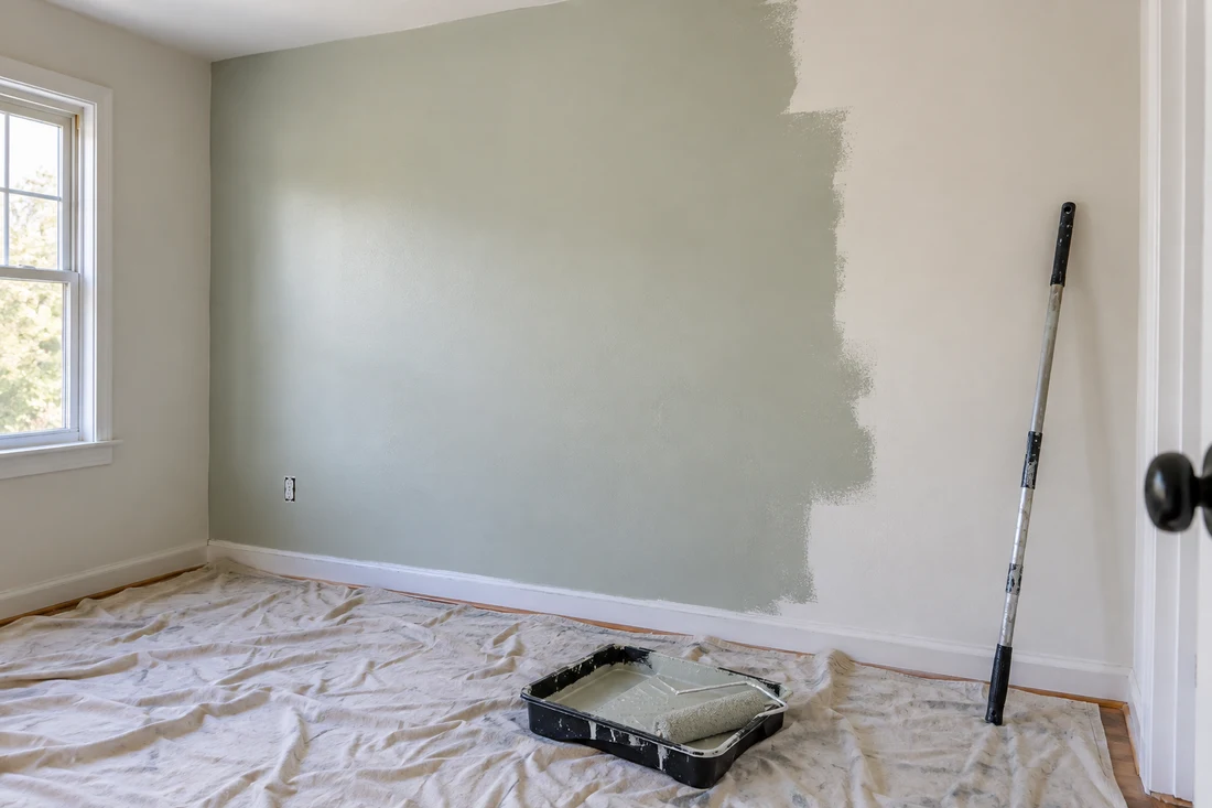 Soft sage wall painting in progress with protected floor